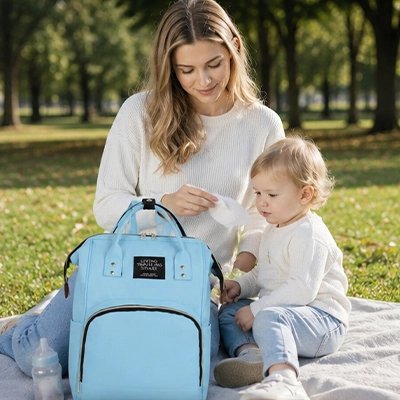 maman et bébé au parc avec sac a dos a langer bleu
