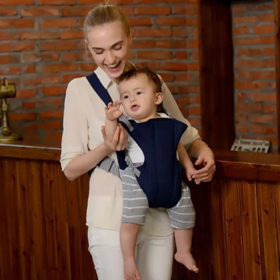 maman riant avec bébé curieux en porte bébé bleu foncé 
